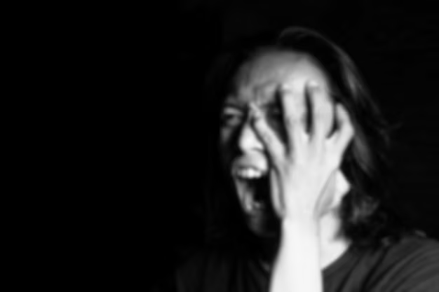 A blurred image of a person with their hands on their head, depicting the distress of emotional triggers.