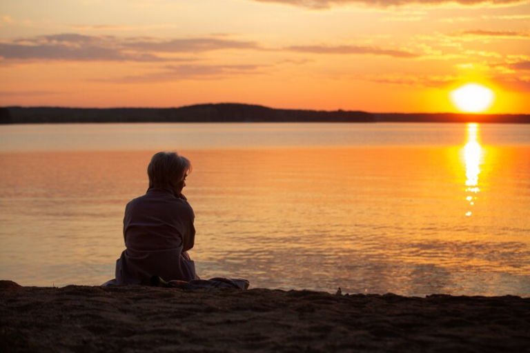 A person sitting on the beach looking at the sunset