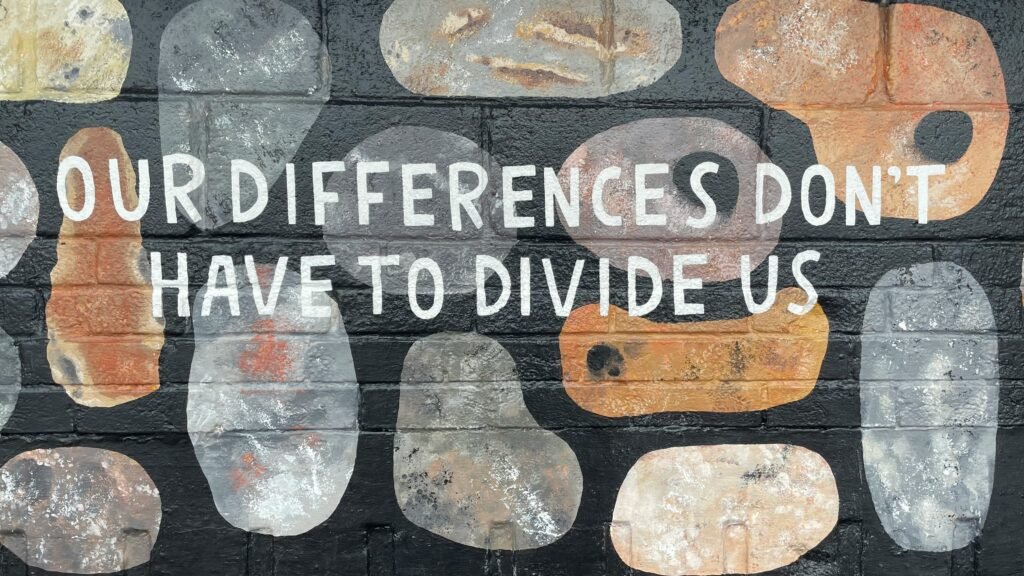 Wall mural reading “Our differences don’t have to divide us” symbolizing unity and inclusion during Minority Mental Health Awareness Month