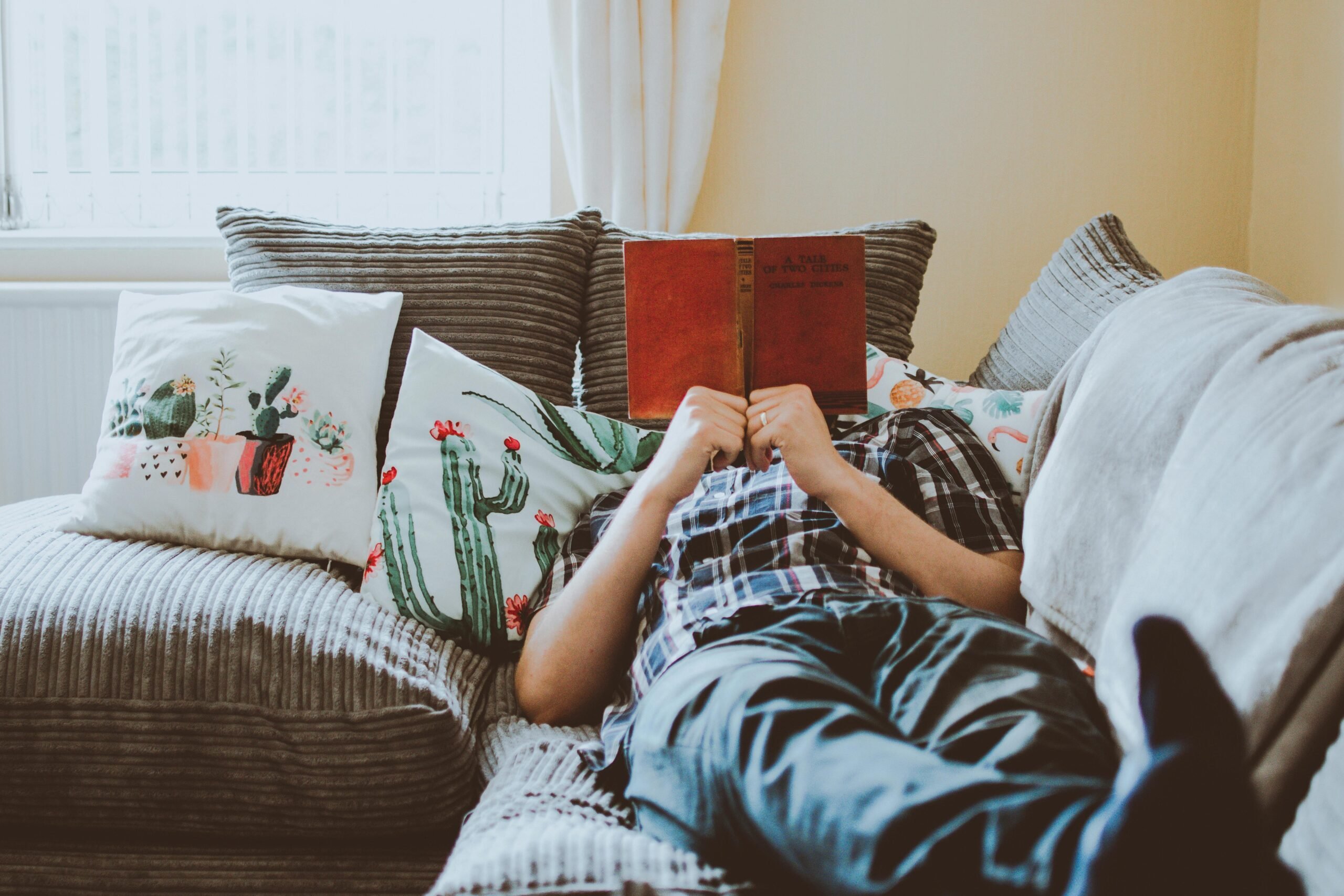 Person relaxing on a couch with a book on National Relaxation Day, supporting long-term recovery and stress relief.