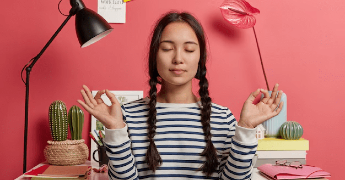 A person sitting at a desk with her eyes closed
