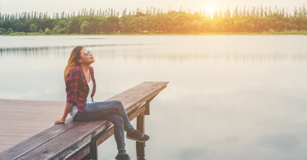 Person reflecting by a lake at sunrise, symbolizing self-forgiveness and healing from guilt and regret.