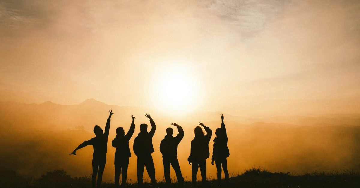 Clarksville recovery community silhouetted at sunrise, arms raised in hope and mutual support