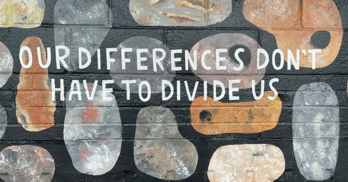 Wall mural reading “Our differences don’t have to divide us” symbolizing unity and inclusion during Minority Mental Health Awareness Month