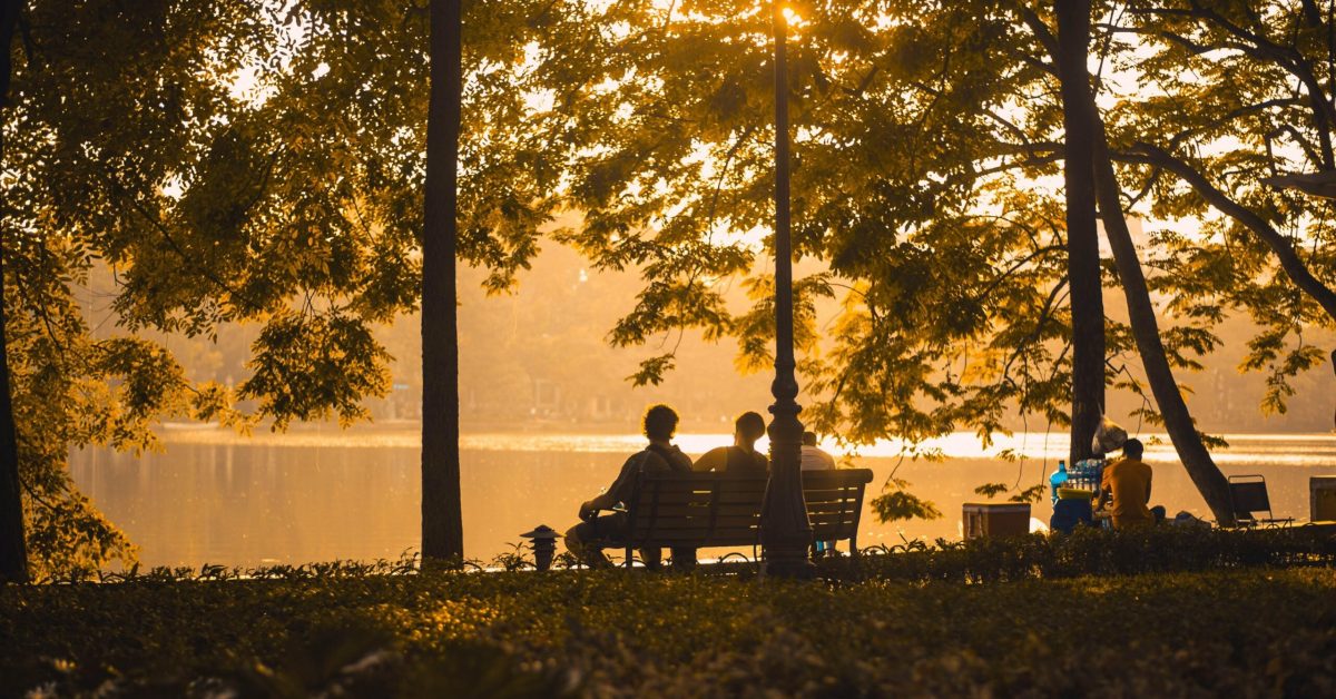 People sitting by the water at sunset on National Grief Awareness Day reflecting and supporting each other