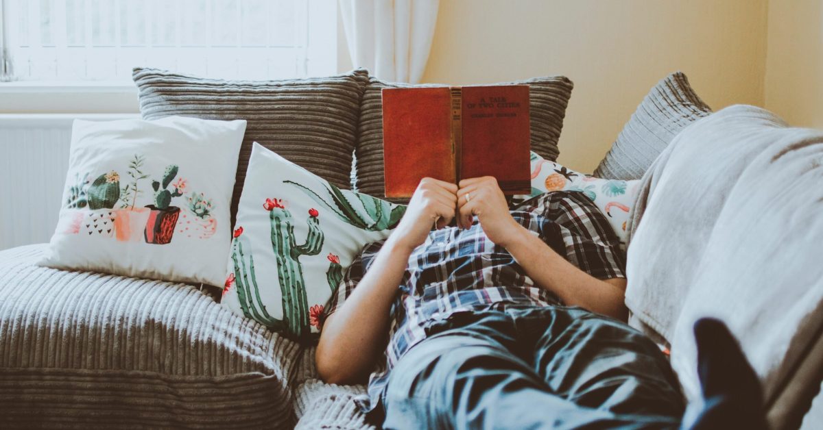 Person relaxing on a couch with a book on National Relaxation Day, supporting long-term recovery and stress relief.